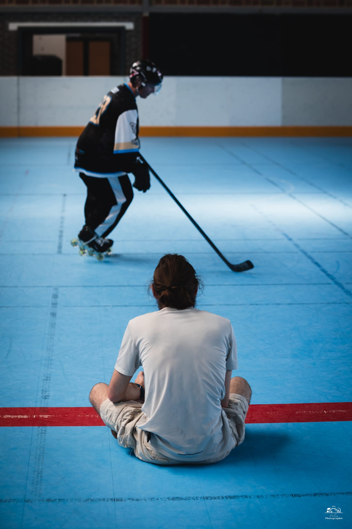 Vue depuis le bord d’un terrain de roller hockey, face à un joueur en action